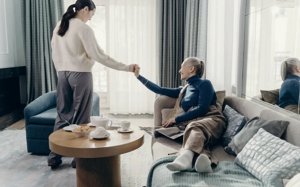 An adult child and an aging parent talking in a bright living room