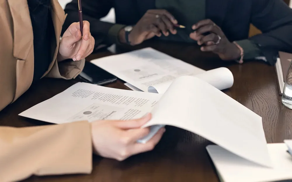 Hands reviewing documents together at a warm wooden table